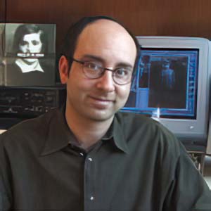 Director David Notowitz of Voices of the Shoah in an office with the book cover behind him